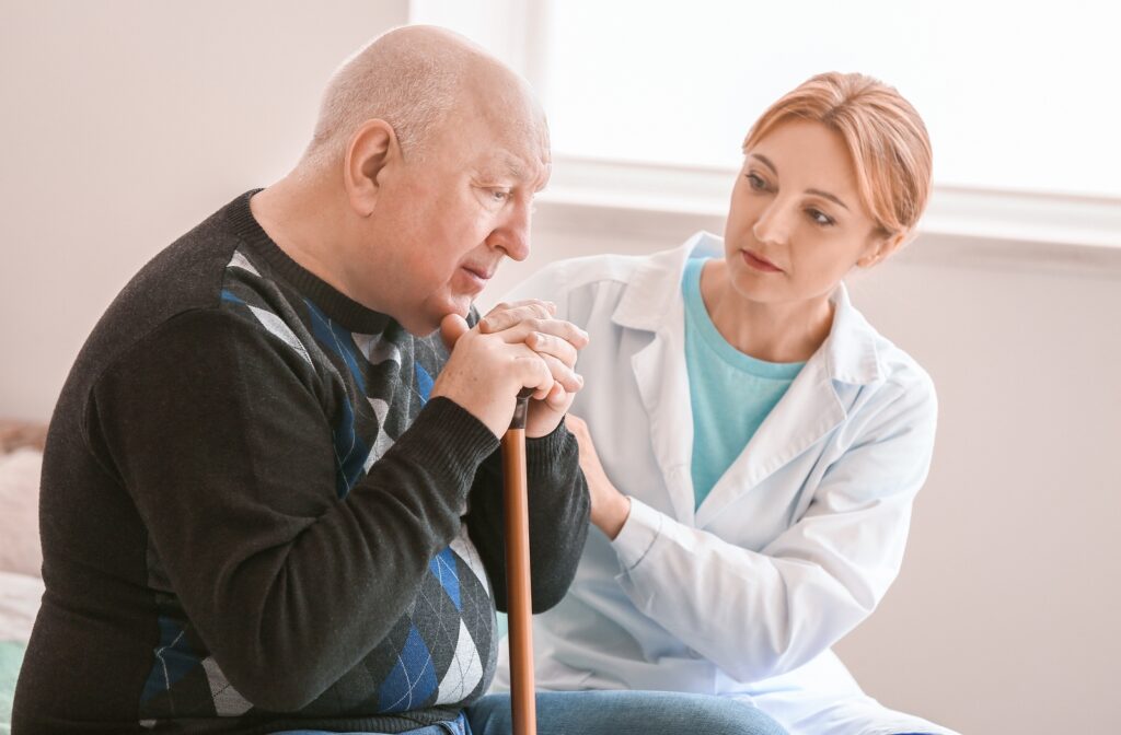 A female nurse consoling a senior citizen man who looks confused and distraught