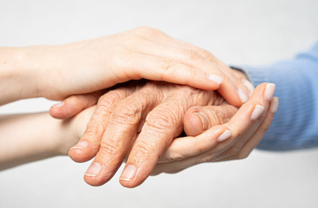 Close-up of a young person's hands as they gently clasp a senior's hand