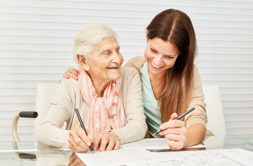 A senior woman and a young woman helping each other to solve a sudoku puzzle.